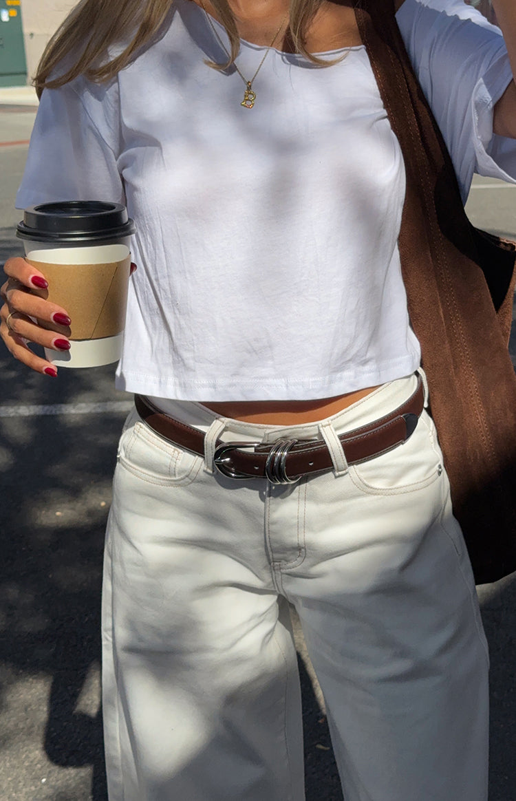 Close-up of the white denim barrel leg jeans waistband with belt loops and visible light contrast stitching