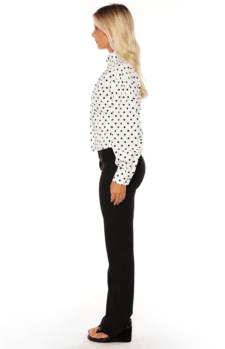 Side view of a white polka dot jacket with a high collar and long cuffed sleeves