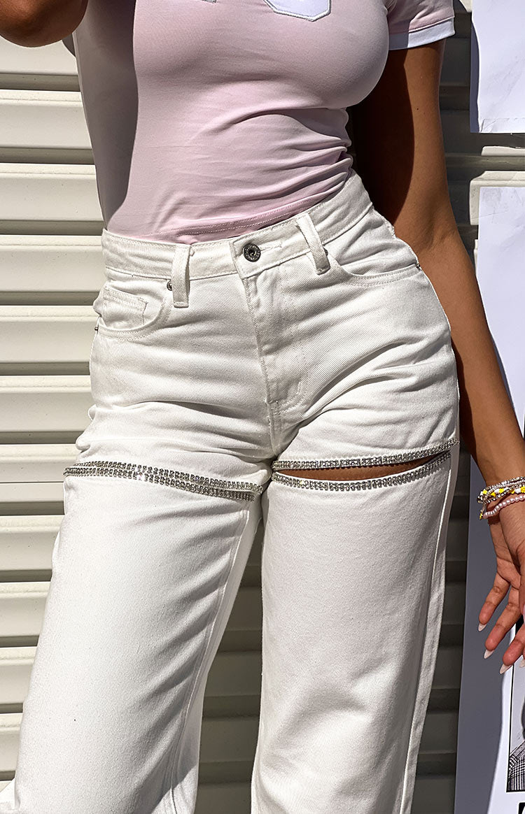 Close-up of white wide-leg denim jeans with diamante trim cutouts across the thighs