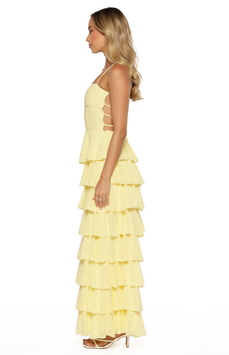 Side view of a yellow tiered ruffle maxi dress showing side cutouts with horizontal straps on the bodice