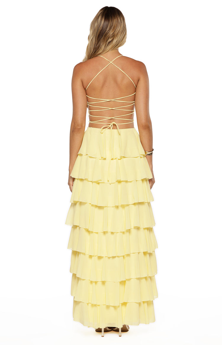 Rear view of a yellow maxi dress with thin criss-cross lace-up back straps and a tiered ruffle skirt