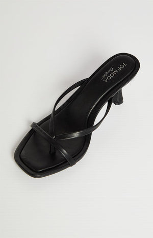 A single black heeled sandal with thin straps is shown on a light background. The sandal has a square toe and a small, curved heel.