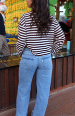 Rear view of light wash denim low rise jeans with white star embroidery on the back pockets