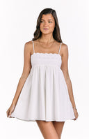 A charming white mini dress with delicate spaghetti straps and a panel of eyelet embroidery across the bust- featuring a flowing skirt- perfect for a casual summer day.
