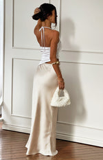 Rear side view of a white halter neck satin maxi dress with tie-back and a flowing light beige skirt