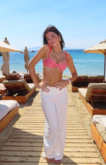 Front view of white wide leg pants with floral cut-out detail on the waistband