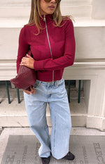 Burgundy knit zip-up sweater with a high collar, full silver zip, and textured star pattern