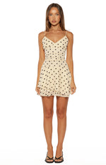 Full front view of the cream polka dot mini dress, showing the sheer waist panel and tiered ruffle skirt