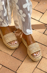 Top-down view of natural raffia platform sandals with a wide woven strap and thick platform sole