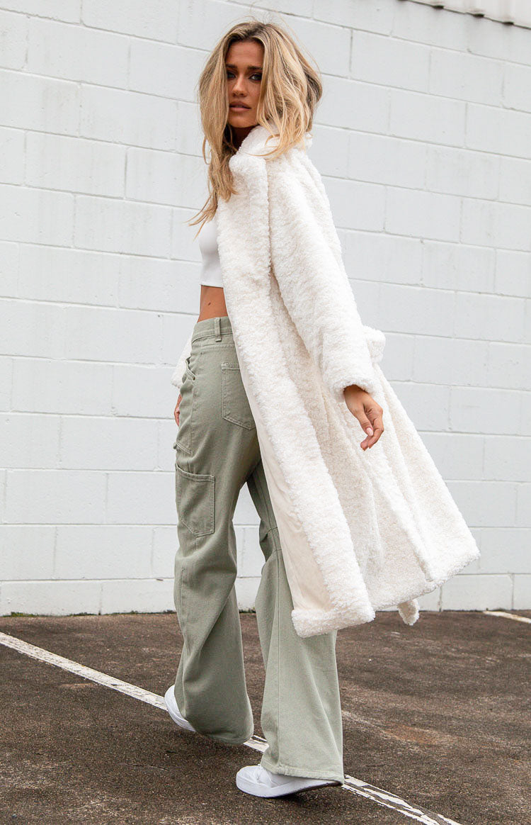 Side view of a long white teddy coat, open to show the smooth inner lining and fluffy texture