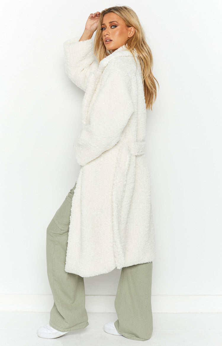Side view of a long white teddy coat with a tie waist, wide lapels, and relaxed fit