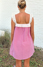 Rear view of a red gingham mini dress with white broderie anglaise ruffled straps and a square back neckline