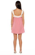 Rear view of a red gingham mini dress with white scalloped lace trim on the ruffled straps and square back
