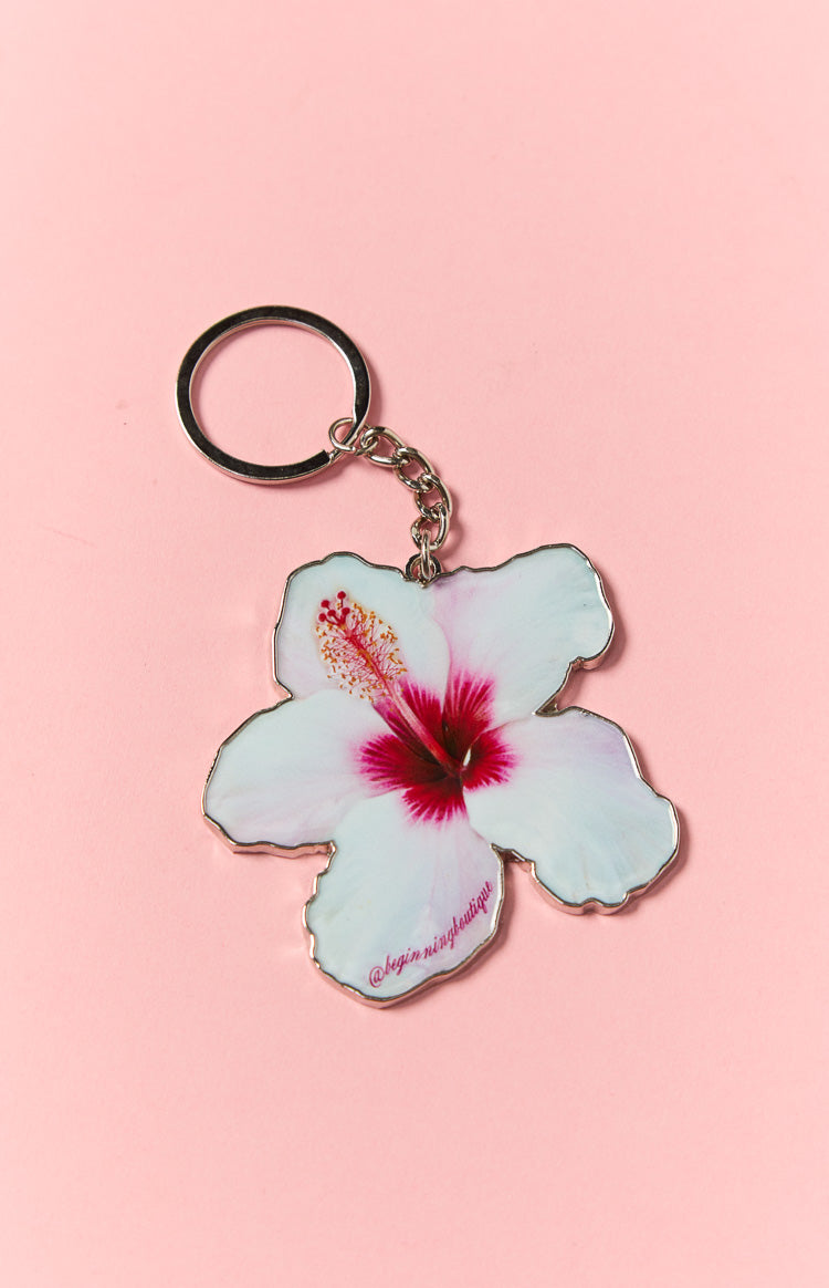 White hibiscus flower key ring with a vibrant pink and red center and silver-toned metal trim