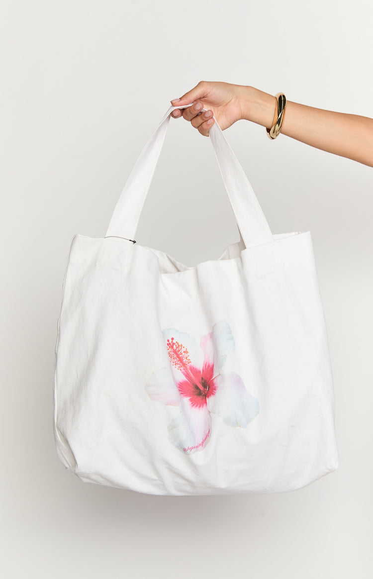 White canvas tote bag with a soft drape, featuring a large pink and white hibiscus flower print