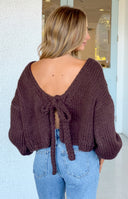 Chocolate brown chunky knit cardigan with an off-shoulder neckline, showing its thick texture and balloon sleeves
