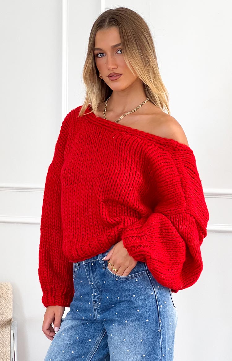 Red chunky knit cardigan styled off-the-shoulder with voluminous long sleeves