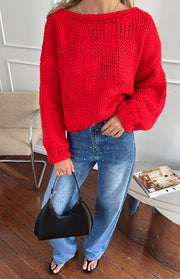 Front view of a red chunky knit cardigan with a wide boat neckline and relaxed long sleeves