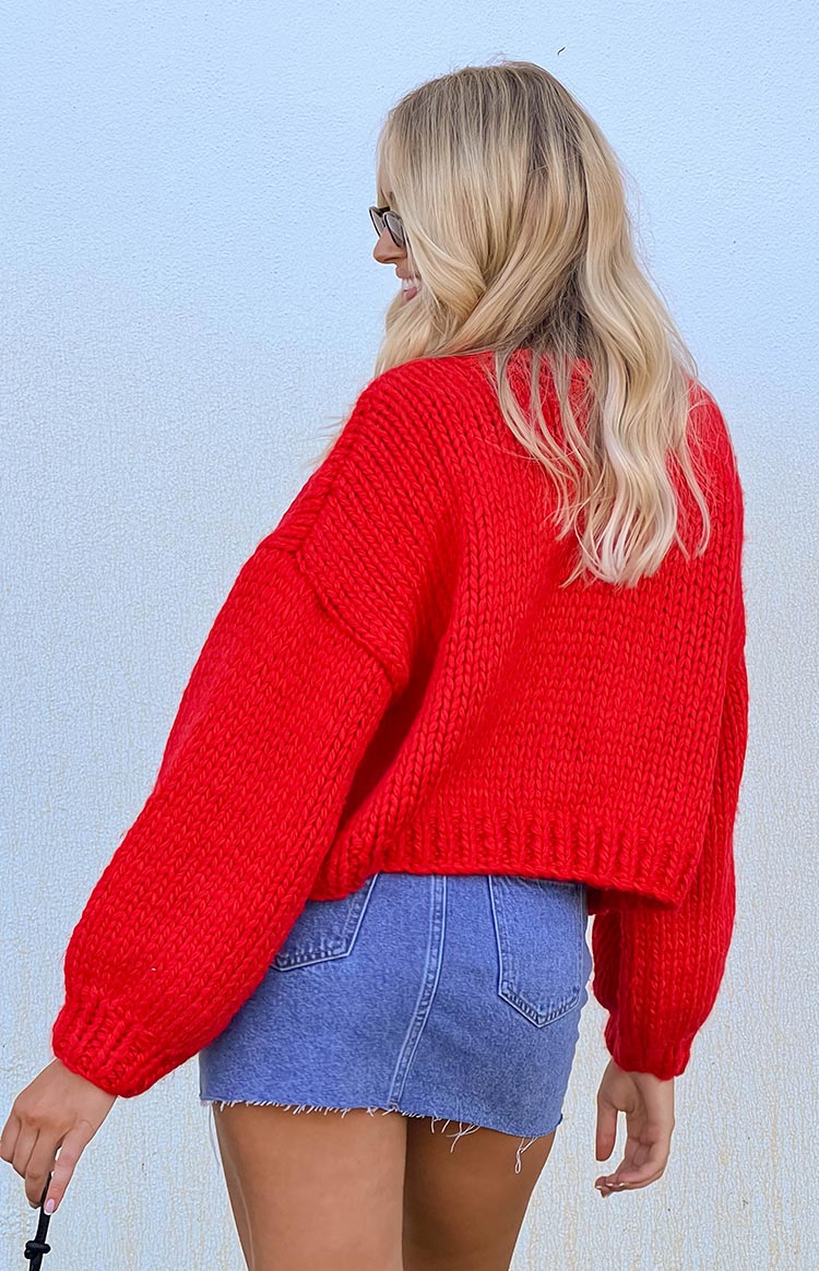 Rear view of a red chunky knit cardigan with voluminous long sleeves and a cropped hem