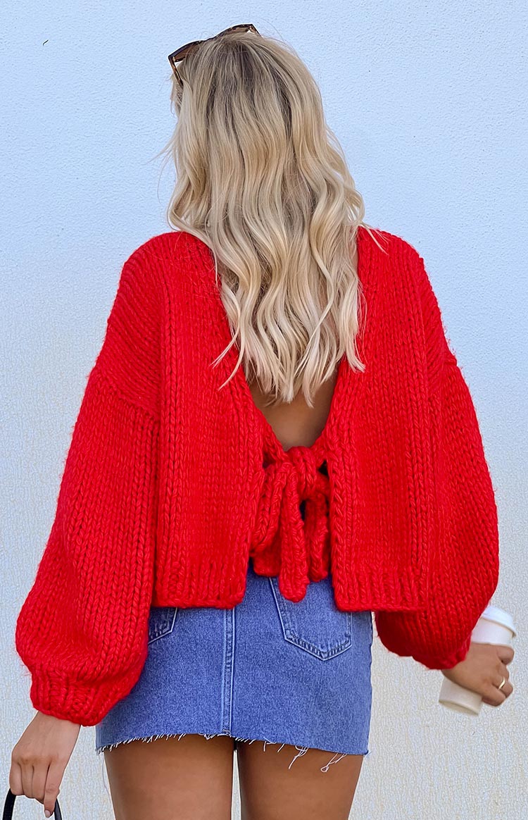 Rear view of a red chunky knit cardigan with an open back, tie closure, and voluminous balloon sleeves