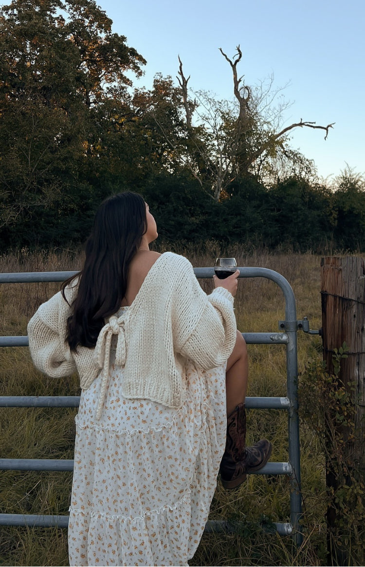 Rear view of a cream chunky knit cardigan with a tie-up open back and long voluminous sleeves