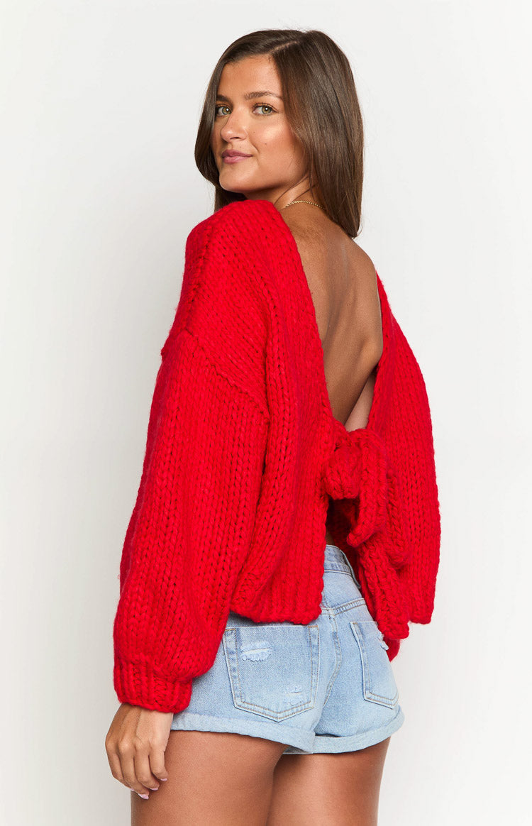 Rear view of a red chunky knit cardigan with a deep scoop back, tie-up detail, and voluminous sleeves