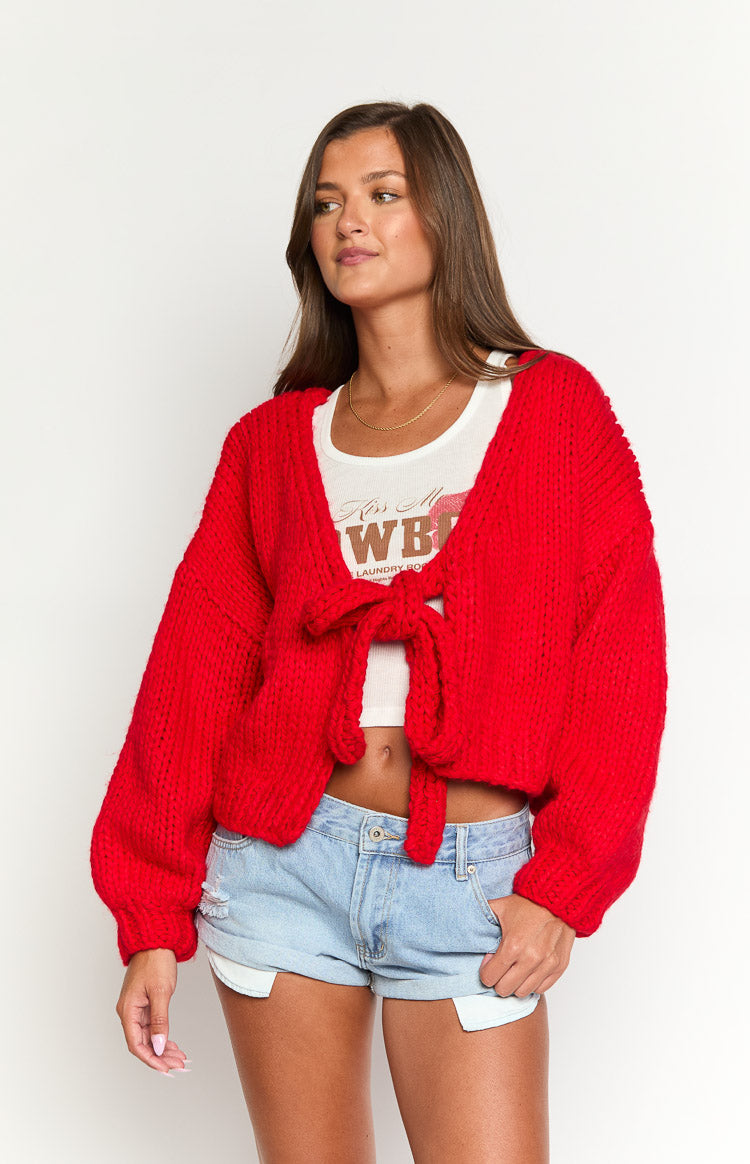 Front view of a red chunky knit tie-up cardigan with long balloon sleeves and a cropped length