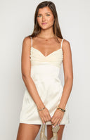 blonde model wearing a cream coloured satin mini dress with a contrast chiffon bust