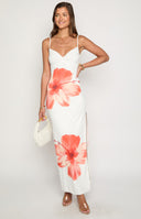 brunette model styled in white maxi dress with flower detailing and leg split