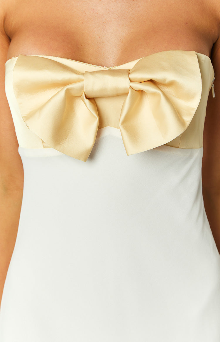 Close-up of the large yellow satin bow on the strapless honeydew yellow bodice and white skirt of the maxi dress