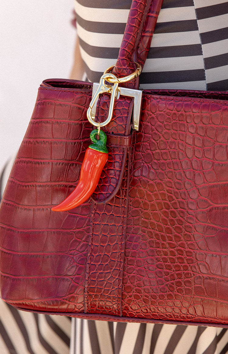 Close-up of the red chilli bag charm with green stem and gold carabiner clip