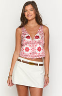 Girl wearing red and white print top and denim mini skirt holding cocktail glass.