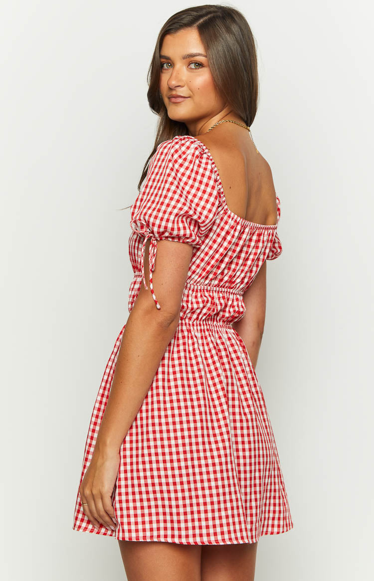 Side view of a red and white gingham mini dress showing the shirred waist and puff sleeves with tie details