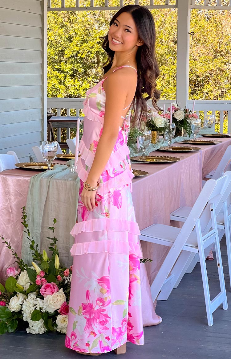Side view of a pink floral print maxi dress with tiered ruffles and criss-cross back straps