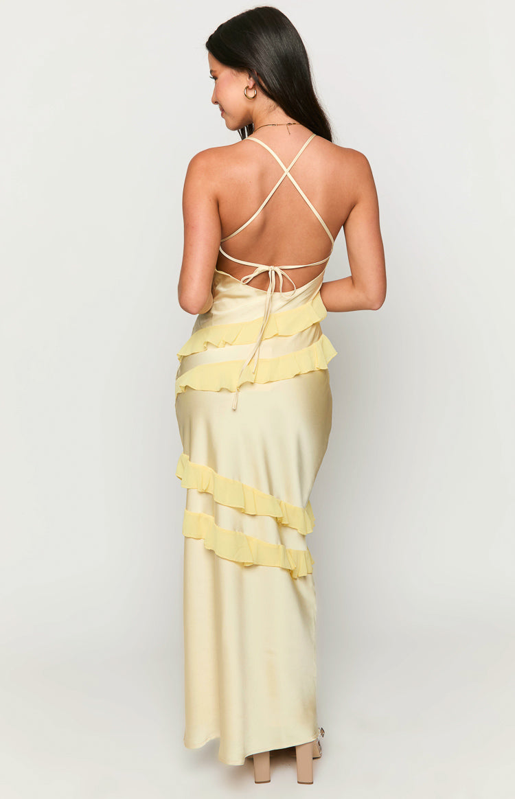 Back view of a pale yellow maxi dress with criss-cross tie-back straps and diagonal tiered ruffles