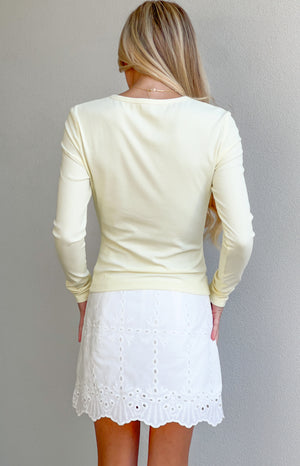 Rear view of a yellow ribbed knit long sleeve top with a round back neckline and fitted silhouette