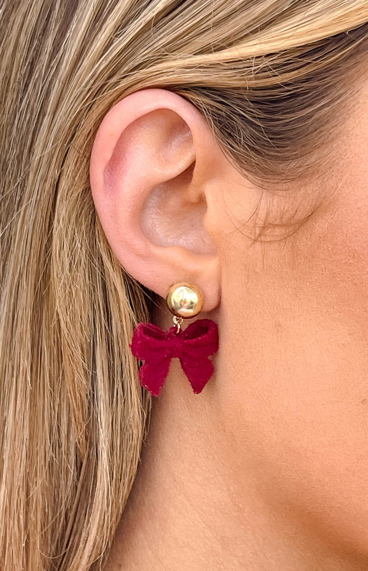 Close-up of a red velvet bow earring with a gold stud