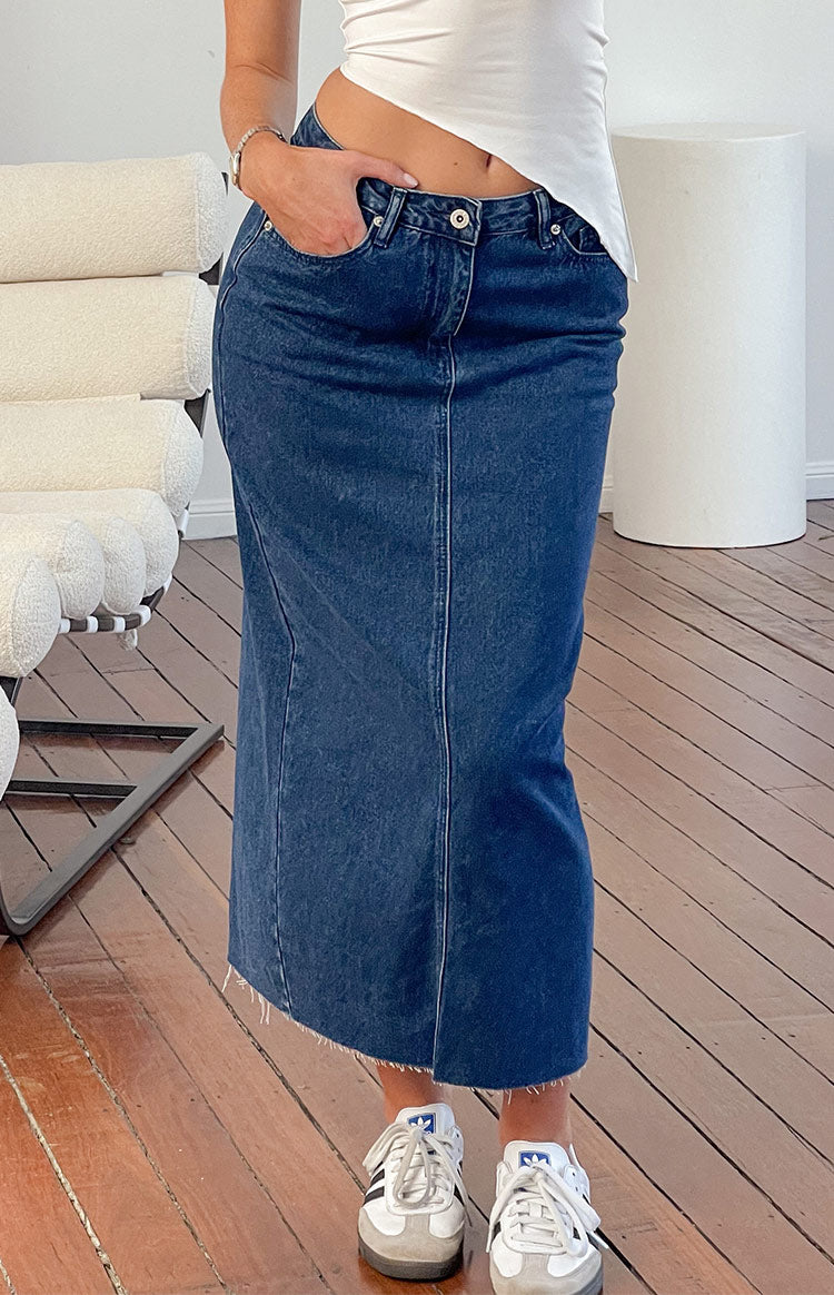 Front view of the dark denim midi skirt showing the button closure, front pockets, and raw frayed hem