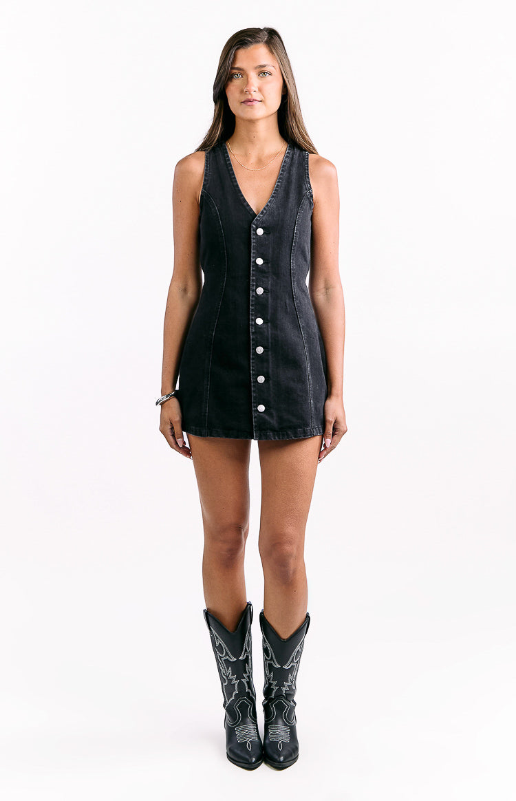 Front view of a black denim mini dress featuring a V-neck, sleeveless design, and white button-front closure