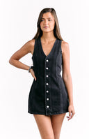 Model wears a sleeveless black denim mini dress for a casual day to night look.