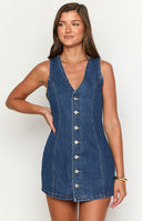 model is wearing a dark wash mini dress with front button detail with cowboy boots