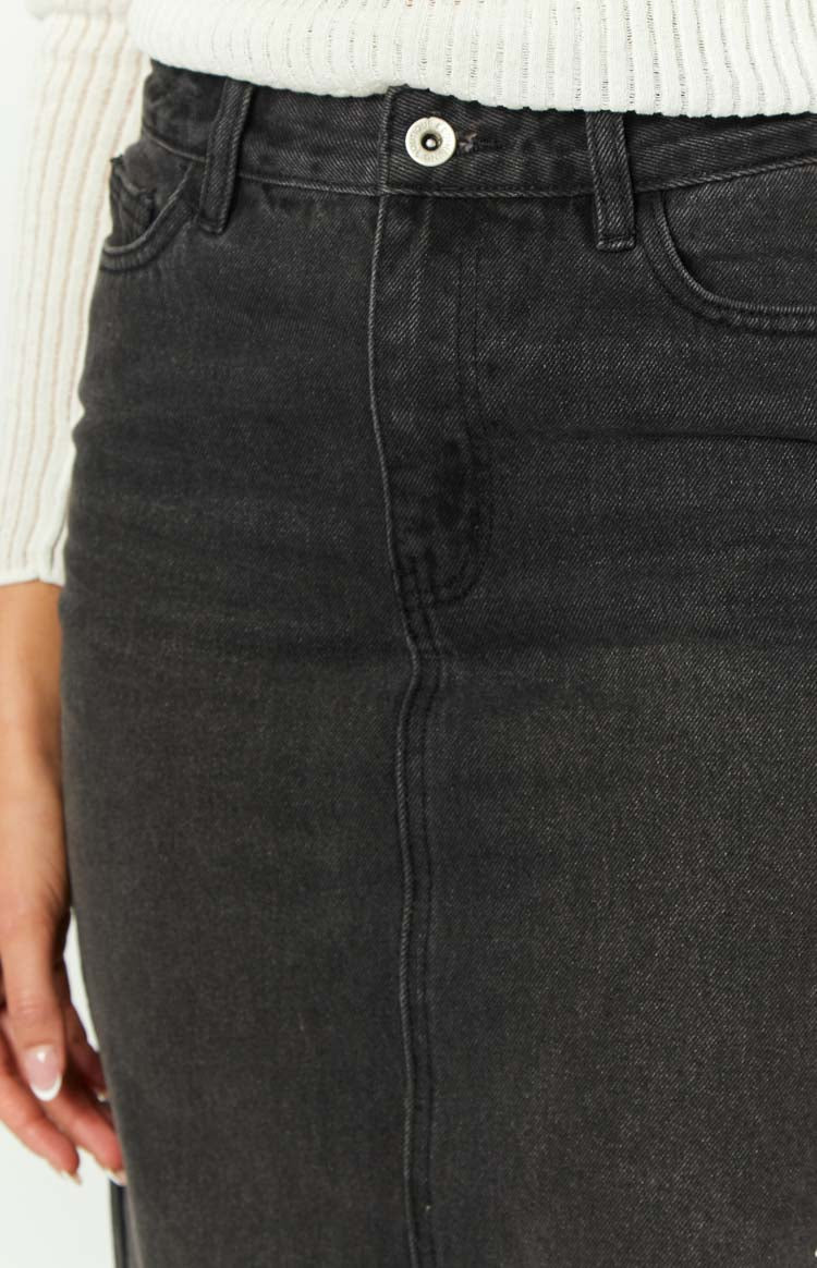 Close-up of the washed black denim midi skirt showing the front button closure and coin pocket