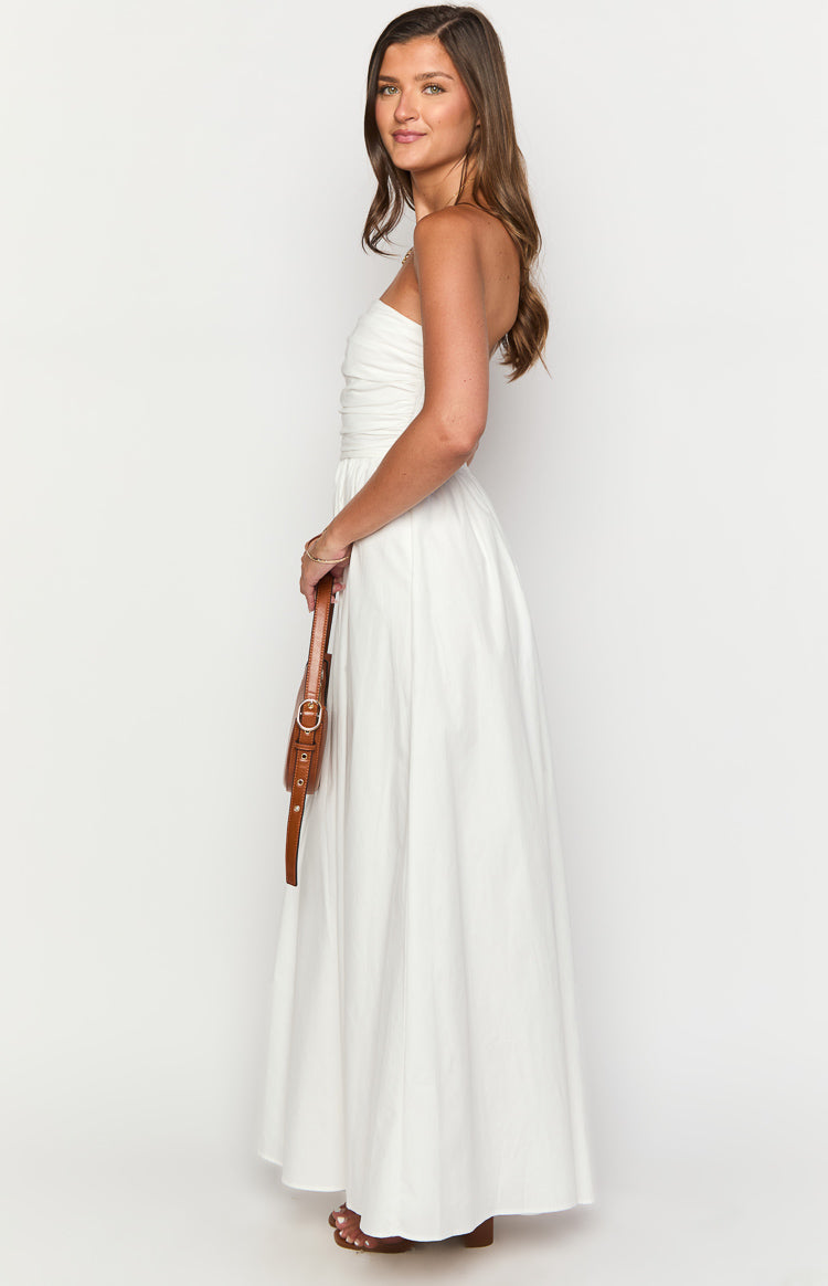 Side view of a white strapless maxi dress with a ruched bodice and a full flowing skirt