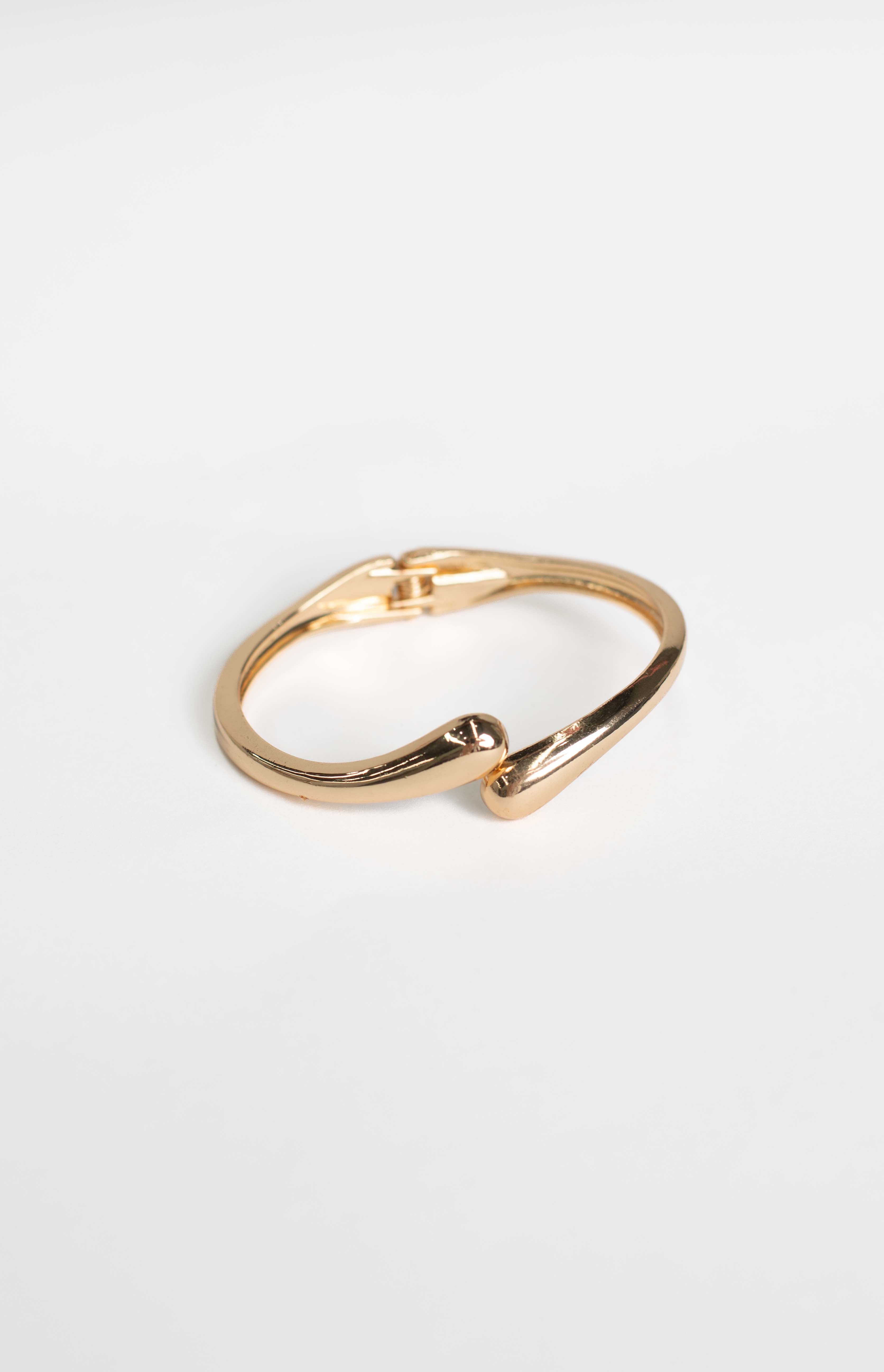 Gold cuff bracelet showing the hinge clasp and the smooth, rounded ends