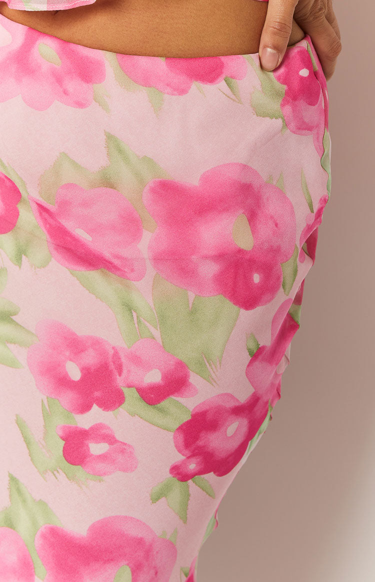 Close-up of the light pink maxi skirt fabric, showing a vibrant floral print with fuchsia flowers and soft green leaves
