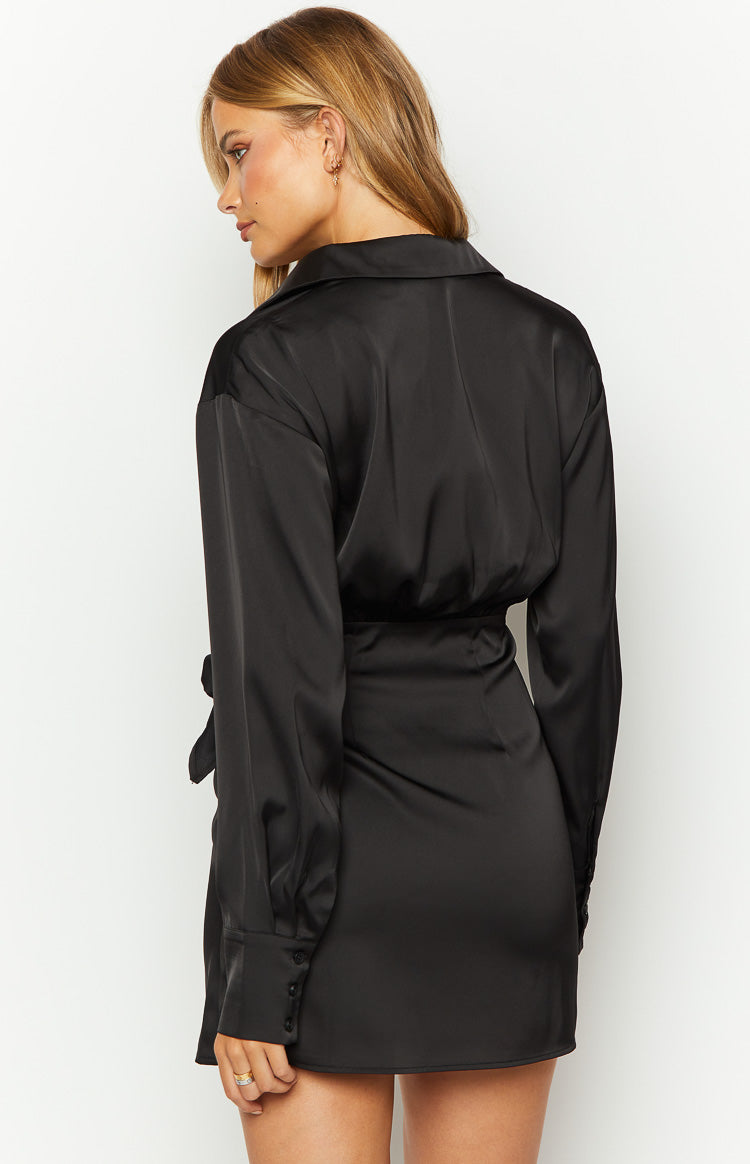 Side view of a black long sleeve mini wrap dress showing the shirred back waist and buttoned cuffs