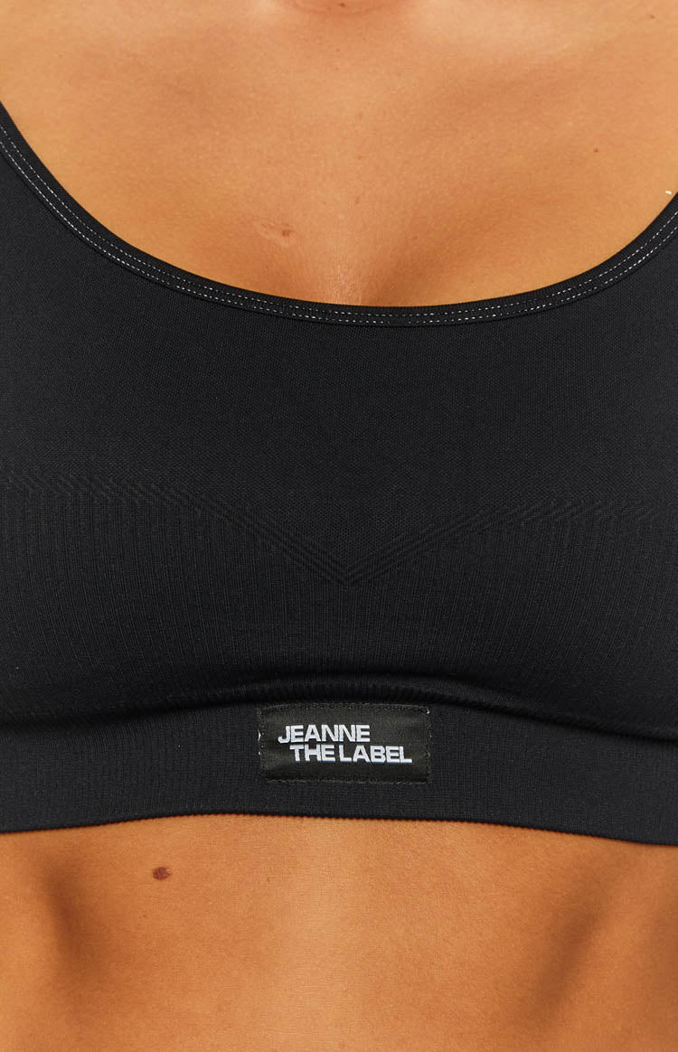 Close-up of black ballet crop top showing white stitching on scoop neckline, subtle chevron texture, and brand label