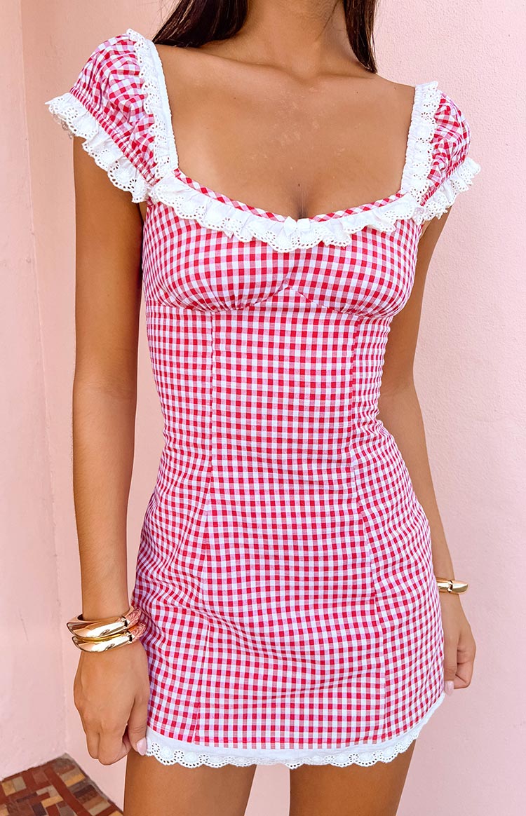Close-up of the red gingham mini dress with white eyelet lace trim on the square neckline, puff sleeves, and hem