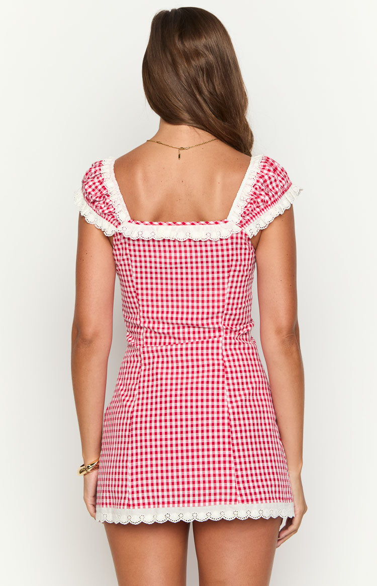 Rear view of a red and white gingham mini dress with a square back neckline and white lace trim on sleeves and hem