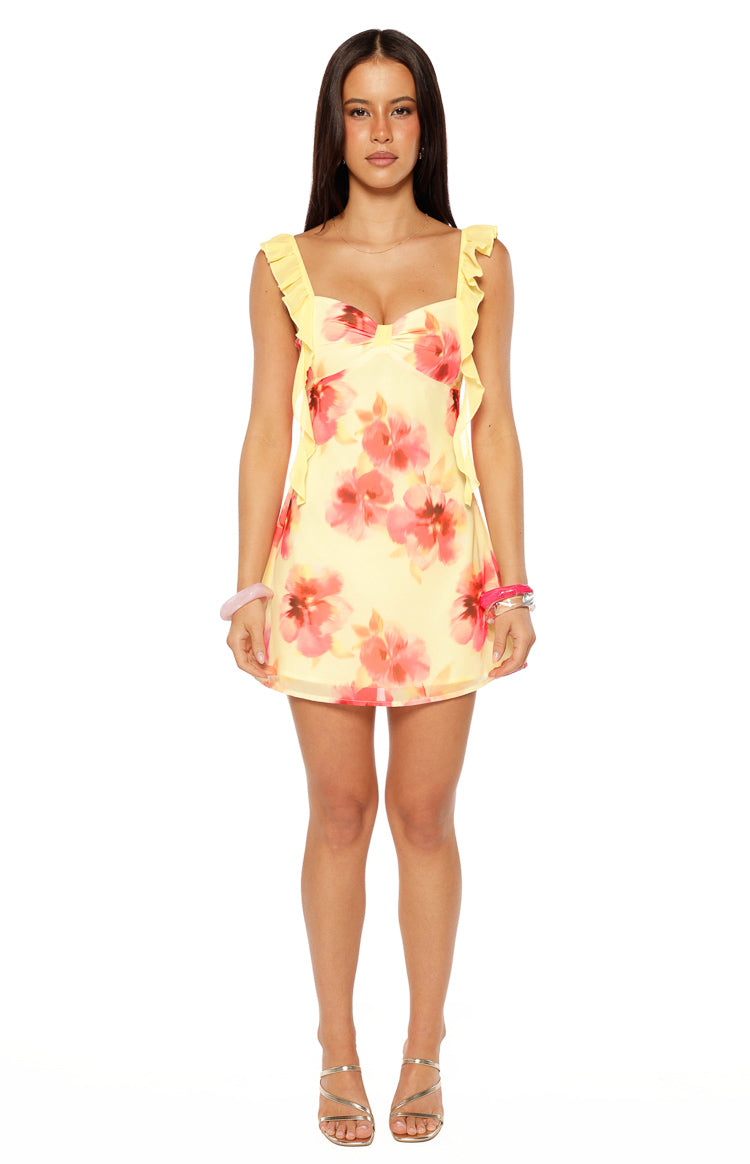 Front view of a yellow chiffon mini dress with pink floral print, sweetheart neckline, and ruffled shoulder straps